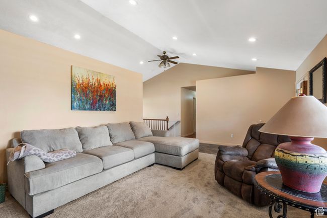 Carpeted living room featuring a ceiling fan, recessed lighting, vaulted ceiling, and baseboards | Image 7