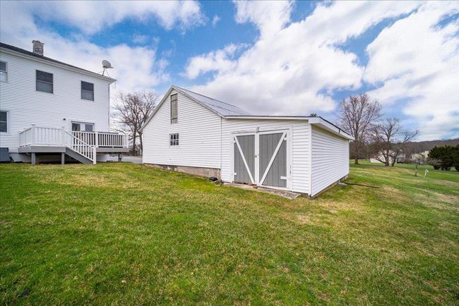 Rear view of house featuring a yard, a deck, a storage shed, and an outbuilding | Image 24