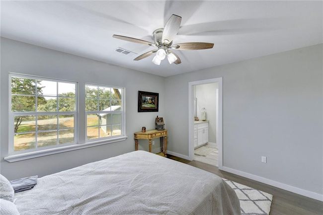 Bedroom featuring wood finished floors, baseboards, ensuite bathroom, and a ceiling fan | Image 14