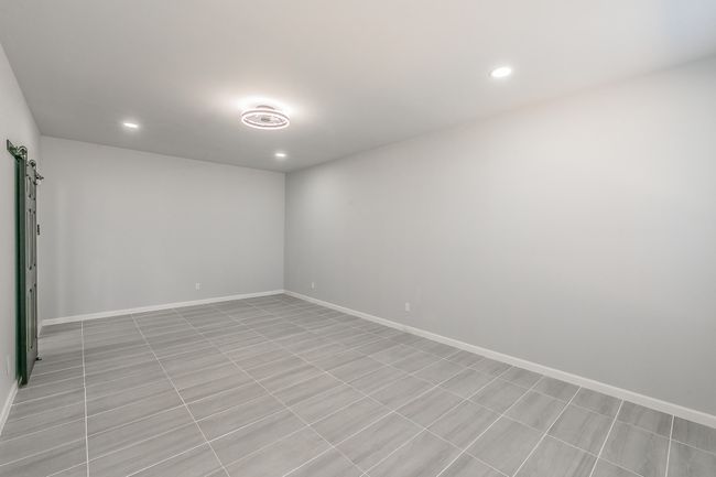 Empty room with baseboards, a barn door, and recessed lighting | Image 10