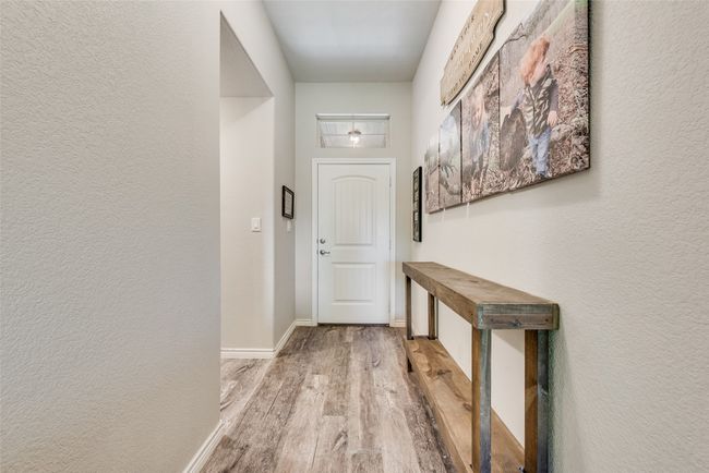 Doorway featuring a textured wall, baseboards, and wood finished floors | Image 7