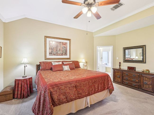 Carpeted bedroom with ornamental molding, connected bathroom, and ceiling fan | Image 16