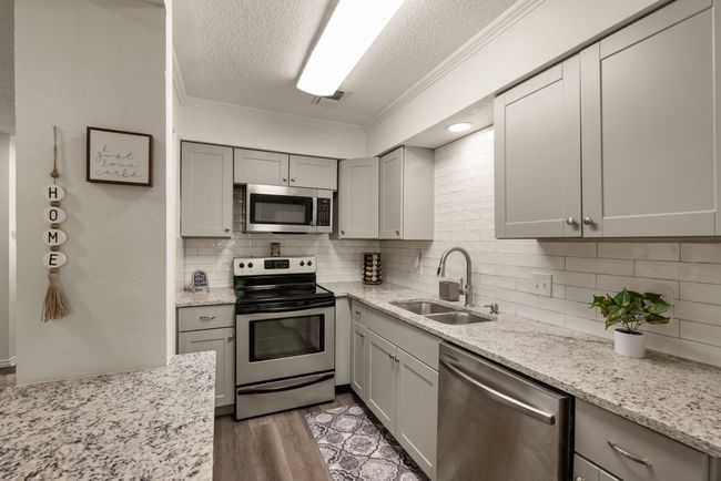 Kitchen featuring a sink, a textured ceiling, backsplash, appliances with stainless steel finishes, and ornamental molding | Image 6