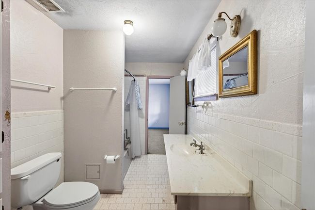 Bathroom featuring a shower with shower curtain, vanity, tile walls, tile patterned flooring, and a wainscoted wall | Image 25