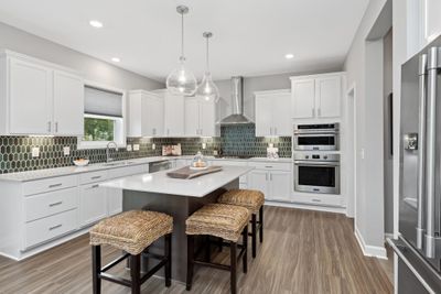 (Photo of a decorated model, actual homes finishes will vary) Welcome to the Lewis! This spacious kitchen features a large center island, quartz countertops, LVP floors, stainless appliances and more. .jpg | Image 2