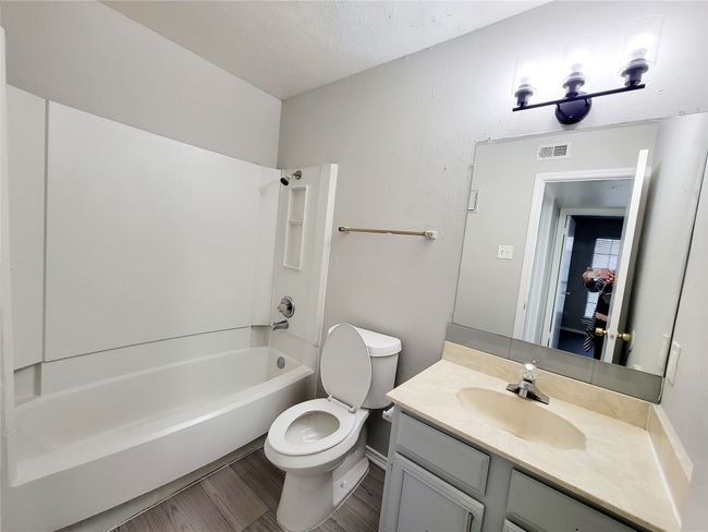 Full bathroom featuring hardwood / wood-style floors, vanity, toilet, a textured ceiling, and tub / shower combination | Image 19