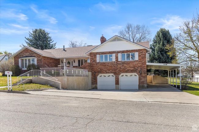 View of front facade with brick siding, driveway, a chimney, and an attached garage | Image 45