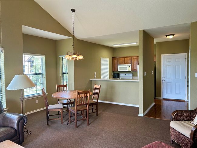 Dining room with a chandelier, baseboards, dark colored carpet, and vaulted ceiling | Image 10