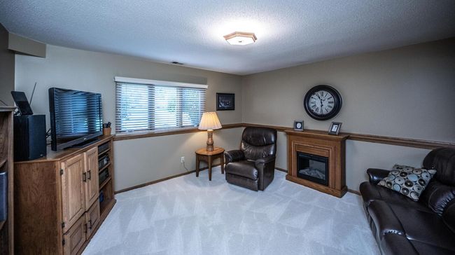 Full lower level features L-shaped family room with electric fireplace, oak ledgers on walls & overhead lighting, two additional bedrooms with laminated flooring, 3/4 bath, utility/laundry room - plus good-sizes lighted storage area under stairs. | Image 25