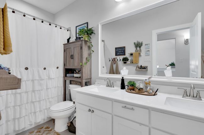 Bathroom with double vanity, tile patterned flooring, and a shower with shower curtain | Image 22