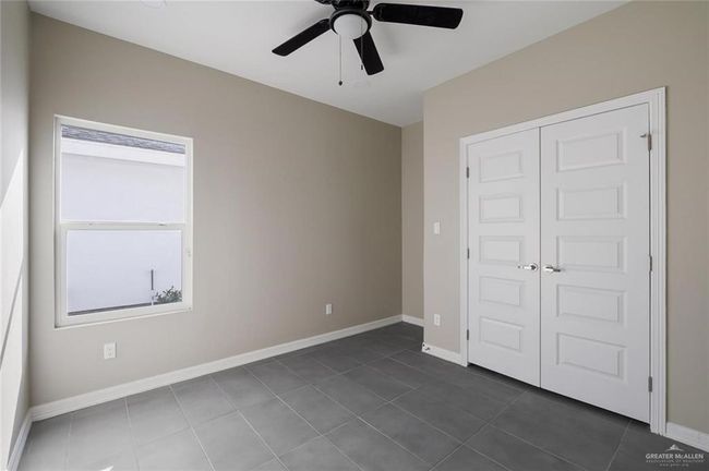 Unfurnished bedroom featuring dark tile patterned flooring, a closet, baseboards, and ceiling fan | Image 13