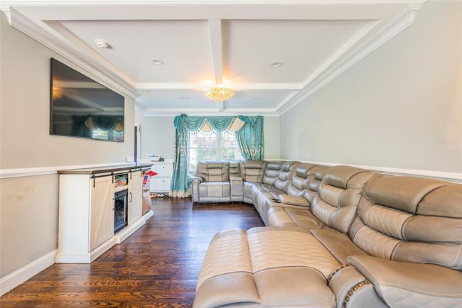 Living area featuring coffered ceiling, dark wood finished floors, crown molding, a fireplace, and beamed ceiling | Image 25
