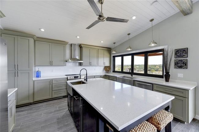 Kitchen with wall chimney range hood, dishwasher, a sink, ceiling fan, and vaulted ceiling | Image 9