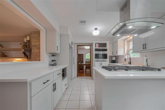 Beautiful new kitchen features sleek built on site new cabinetry, a central island with a gas cooktop and contemporary range hood, and ample counter space offering a warm and inviting atmosphere for cooking and entertaining. | Image 11