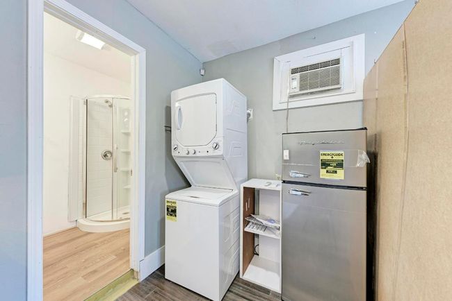 Clothes washing area with a wall mounted air conditioner, wood finished floors, and stacked washer / dryer | Image 35