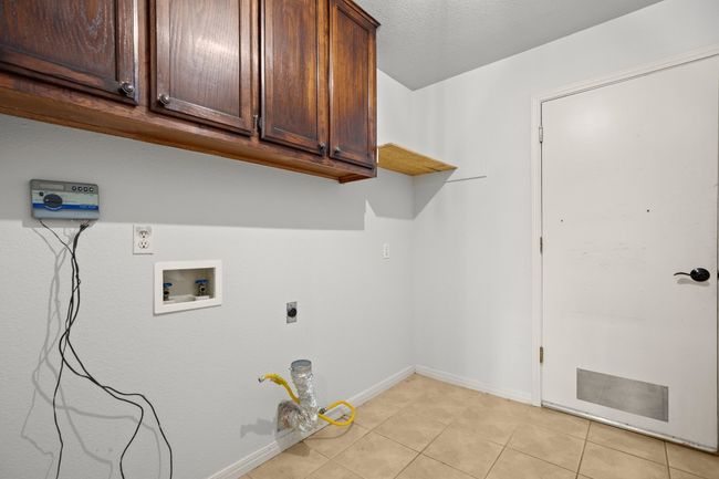 Washroom featuring light tile patterned floors, hookup for a washing machine, electric dryer hookup, and cabinet space | Image 25