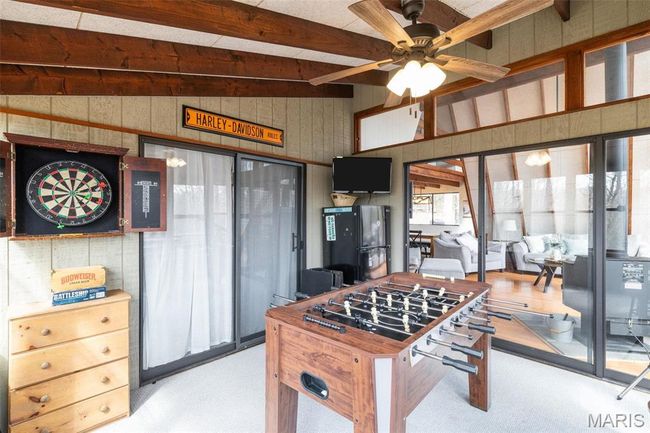 Recreation room with wooden walls, lofted ceiling with beams, ceiling fan, and carpet floors | Image 31