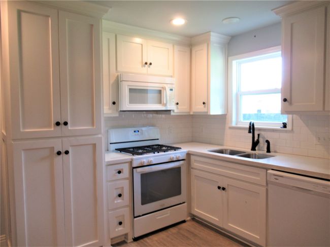 Kitchen with light countertops, a sink, light wood-type flooring, and white appliances | Image 10