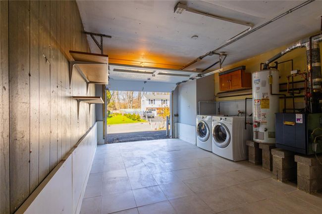 Garage featuring laundry area with water heater, independent washer and dryer, and wood clad walls | Image 22