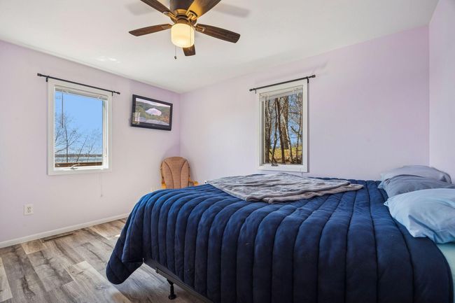 The first of two main floor bedrooms offers LVP flooring, a ceiling fan for added comfort, two windows that bring in plenty of natural light, and a spacious double closet for ample storage. | Image 7