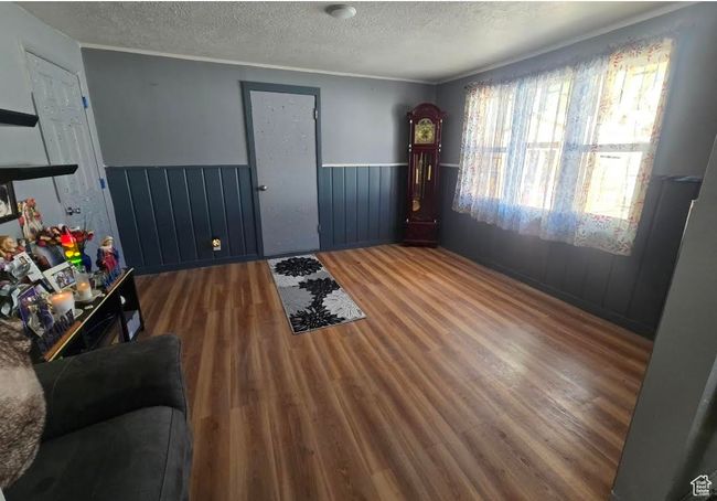 Interior space with wood finished floors, a textured ceiling, and a wainscoted wall | Image 16