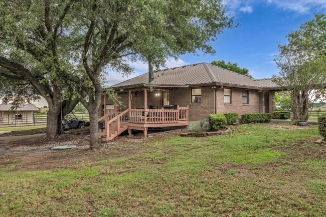 Rear view of house with a metal roof, a deck, and brick siding | Image 18