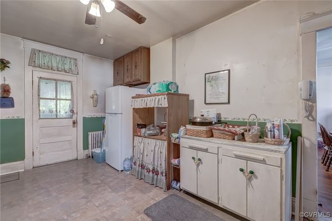 Kitchen featuring light countertops, a ceiling fan, radiator, and white cabinetry | Image 12