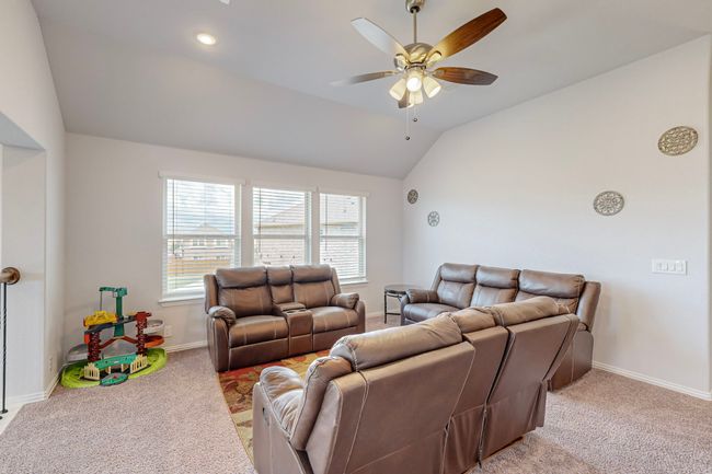 Living room with carpet flooring, baseboards, lofted ceiling, and ceiling fan | Image 30