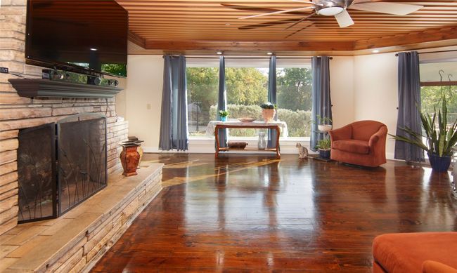 The large great room is split by this lovely stone fireplace, which also has a three sided water feature! The floor to ceiling windows and glass doors allow so much natural light. | Image 7