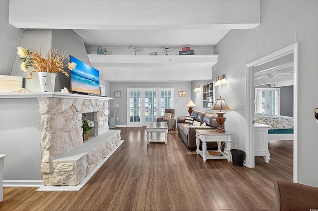 Living area featuring wood finished floors, a ceiling fan, a stone fireplace, and a textured wall | Image 13