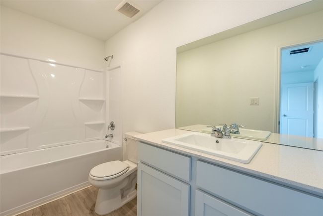 Full bathroom featuring wood finished floors, vanity, toilet, and tub / shower combination | Image 11