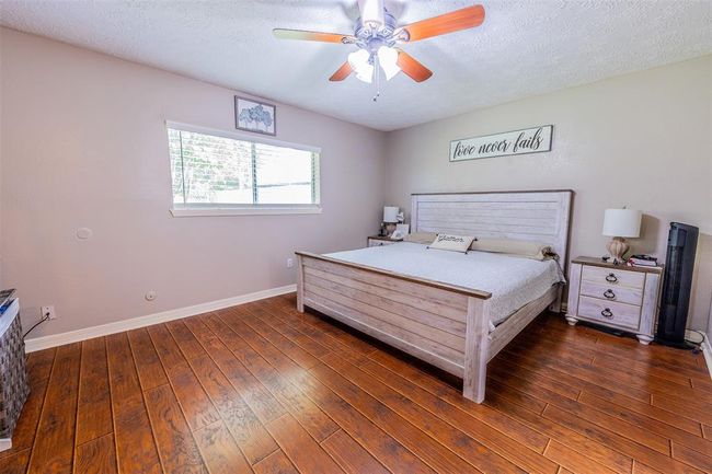 This cozy primary bedroom is brightened by a large window and ceiling fan, offering a comfortable and inviting atmosphere. | Image 25