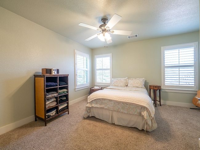 Bedroom featuring light carpet, a ceiling fan, and a textured ceiling | Image 19