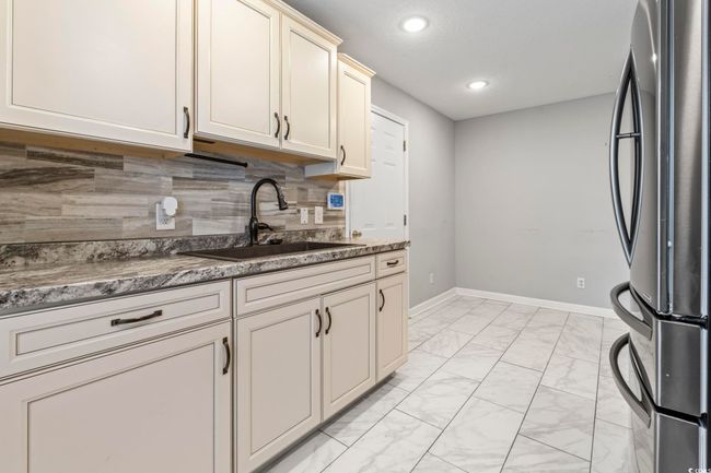 Kitchen featuring freestanding refrigerator, light marble finish flooring, recessed lighting, and tasteful backsplash | Image 10