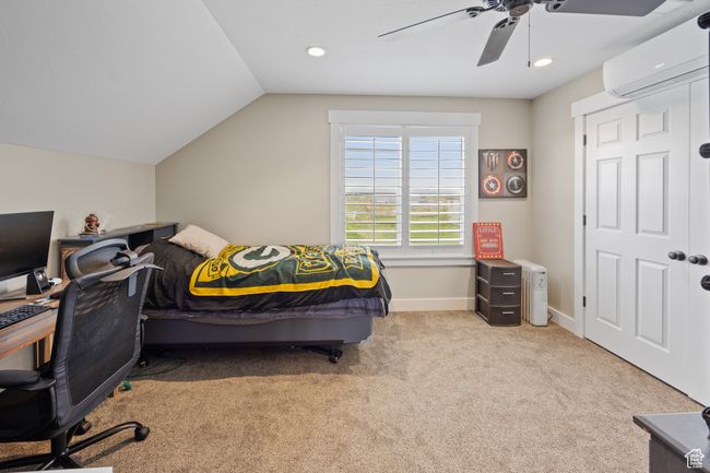 Bedroom featuring an AC wall unit, carpet flooring, vaulted ceiling, ceiling fan, and baseboards | Image 56