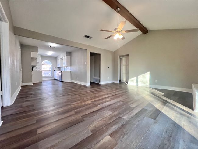 Unfurnished living room with ceiling fan, dark hardwood / wood-style flooring, and lofted ceiling with beams | Image 14