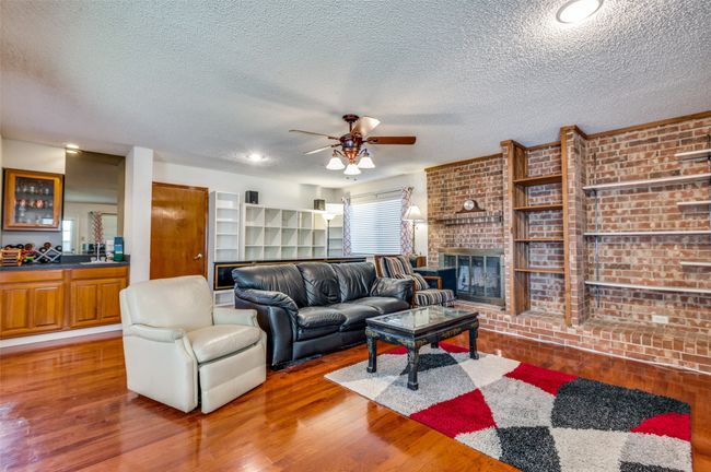 Living room with wood finished floors, brick wall, and a ceiling fan | Image 5