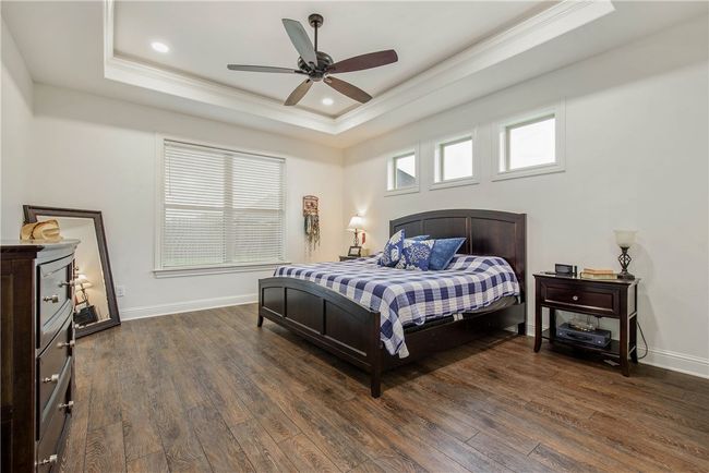 Bedroom featuring a tray ceiling, crown molding, baseboards, and wood finished floors | Image 14