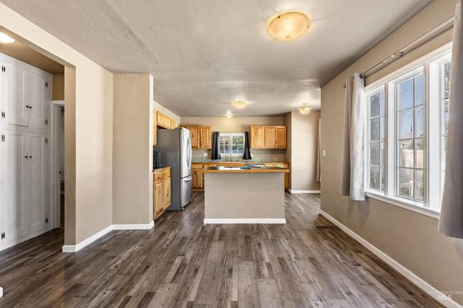 Kitchen with light countertops, dark wood-style floors, freestanding refrigerator, a textured ceiling, and a center island | Image 10