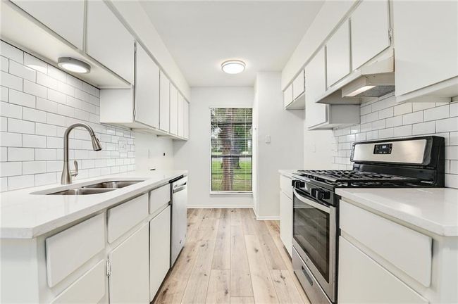 Kitchen with appliances with stainless steel finishes, a sink, under cabinet range hood, light countertops, and tasteful backsplash | Image 21
