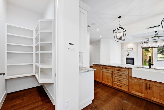 Kitchen featuring dark wood-type flooring, a sink, light stone counters, a chandelier, and hanging light fixtures | Image 13