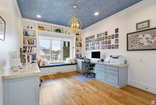Home office featuring baseboards, an inviting chandelier, built in desk, an ornate ceiling, and light wood-style flooring | Image 16