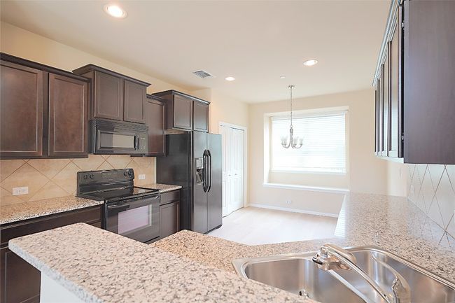 Kitchen featuring black appliances, a chandelier, dark brown cabinets, tasteful backsplash, and pendant lighting | Image 5