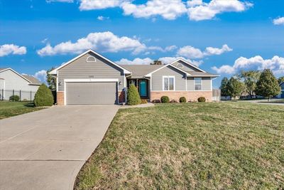 Ranch-style house with a front yard and a garage | Image 1