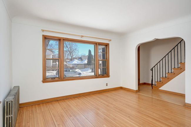 The living room is drenched in natural light and boasts gleaming original hardwood flooring. | Image 4