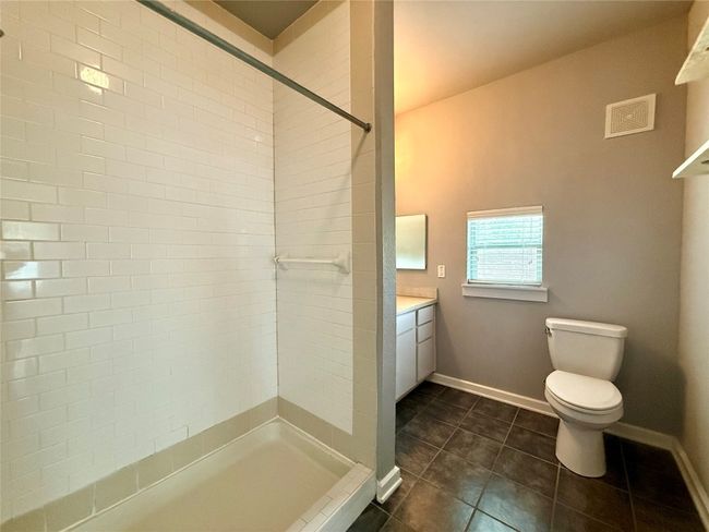 Full bathroom featuring toilet, vanity, tile patterned floors, baseboards, and a tile shower | Image 10