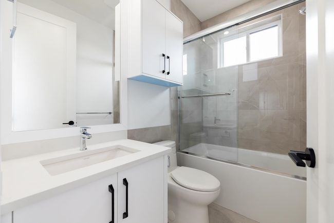 Bathroom featuring vanity and bath / shower combo with glass door | Image 35
