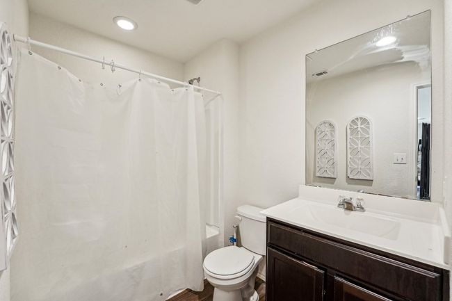 Bathroom featuring visible vents, toilet, shower / tub combo with curtain, and vanity | Image 13