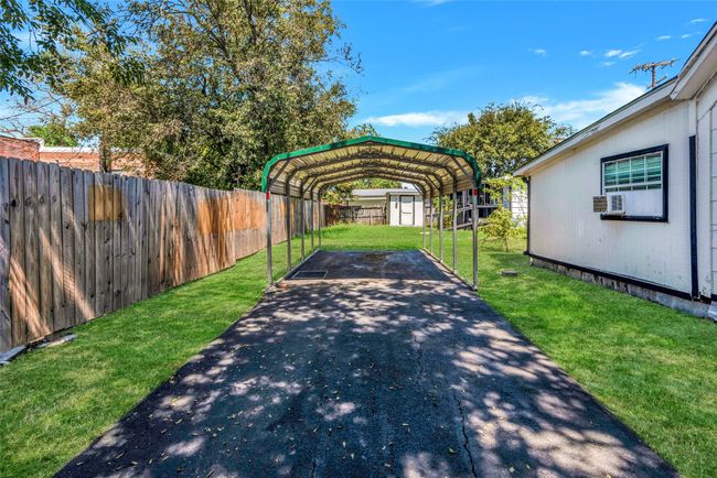Fenced backyard featuring driveway, a carport, and a storage unit | Image 8