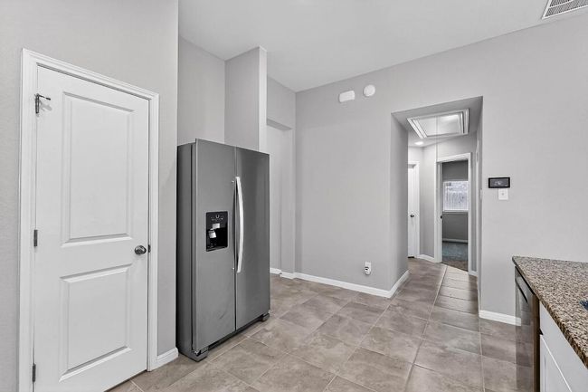 Kitchen featuring stainless steel fridge with ice dispenser, light stone countertops, and light tile patterned floors | Image 14